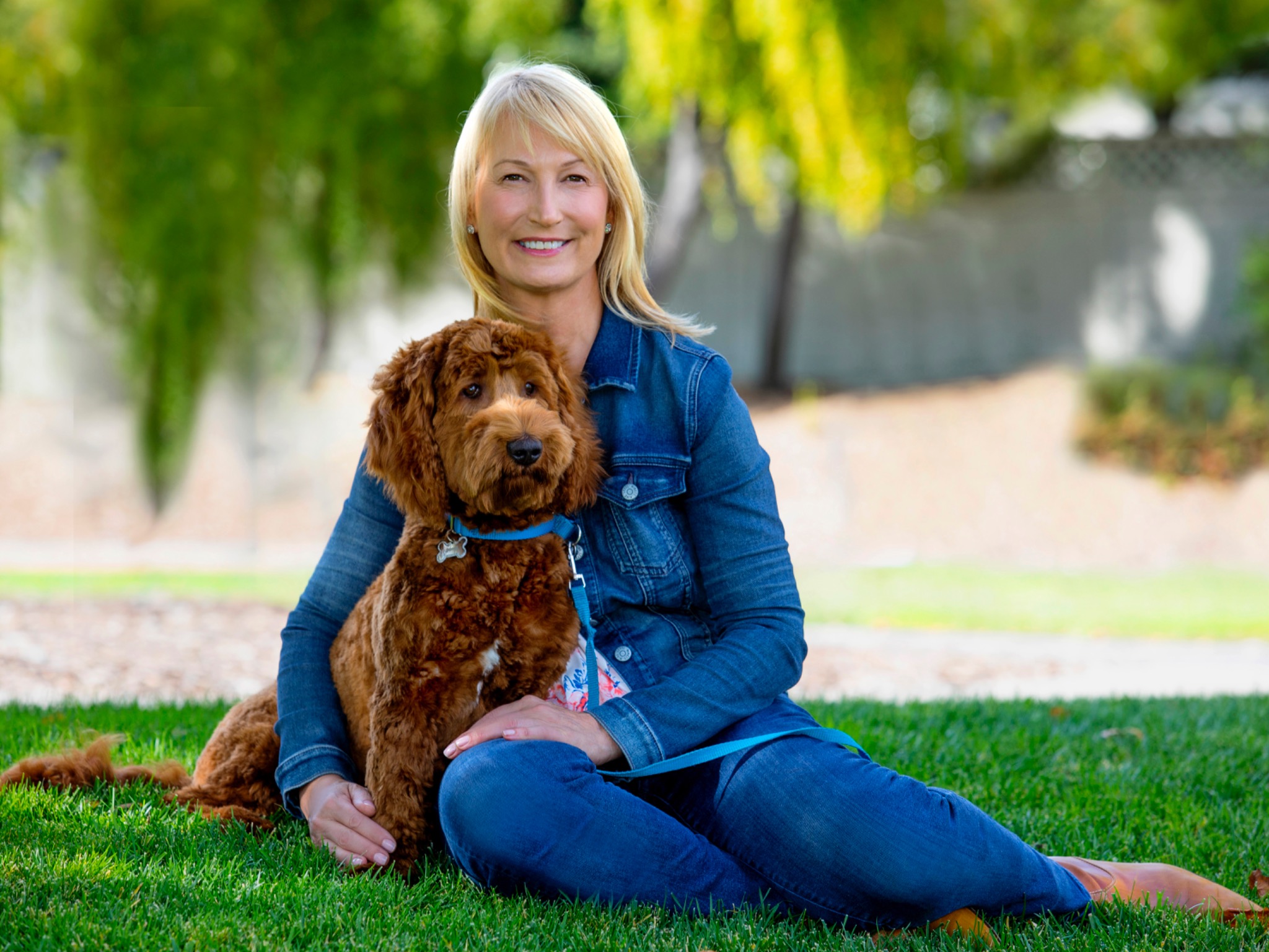 Heidi Diebel sitting outdoors with Ringo, her brown Australian Labradoodle